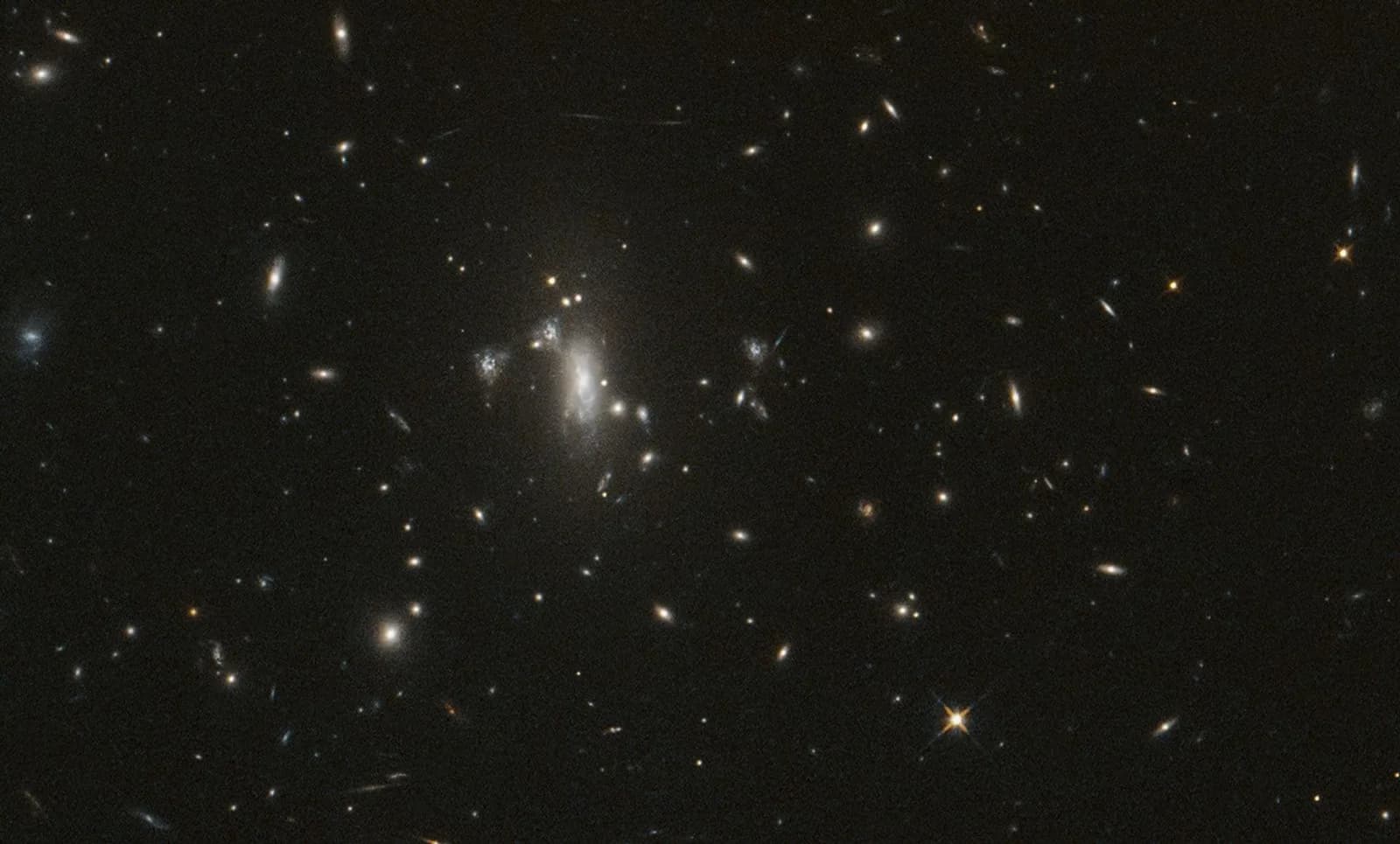 Hubble view of the galaxy cluster MACS J0417 against a dark field of distant galaxies.